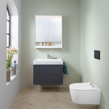 Невелика ванна кімната в м’ятному кольорі із шафкою під умивальник кольору лави, дзеркальною шафою, змивною клавішею та керамікою від Geberit